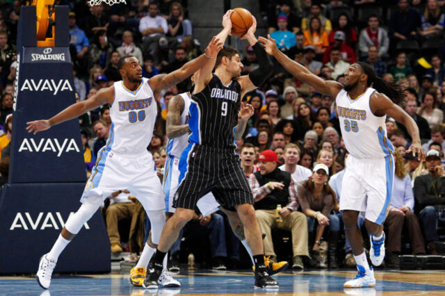 Orlando Magic center Nikola Vucevic (9) controls the ball against Denver Nuggets forward Darrell Arthur (00) and forward Kenneth Faried (35) in the second quarter at Pepsi Center.