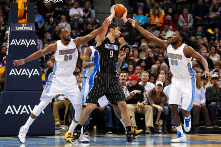 Orlando Magic center Nikola Vucevic (9) controls the ball against Denver Nuggets forward Darrell Arthur (00) and forward Kenneth Faried (35) in the second quarter at Pepsi Center.