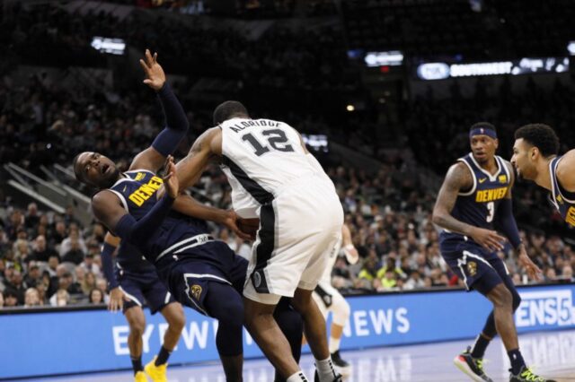 Denver Nuggets power forward Paul Millsap (left) draws a charge from San Antonio Spurs power forward LaMarcus Aldridge (12) during the first half at AT&T Center.