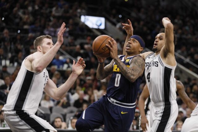 Denver Nuggets point guard Isaiah Thomas (0) drives to the basket as San Antonio Spurs point guard Derrick White (4) and Jakob Poeltl (left) defend during the first half at AT&T Center.