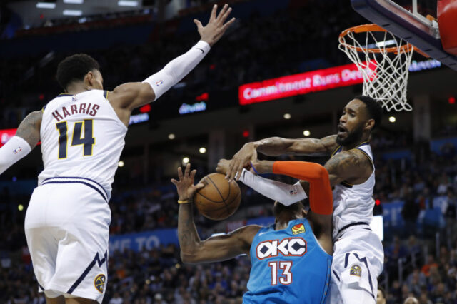 Oklahoma City, OK, USA; Oklahoma City Thunder forward Paul George (13) is fouled by Denver Nuggets guard Will Barton (5) as guard Gary Harris (14) defends during the second half at Chesapeake Energy Arena. Denver won 115-105.