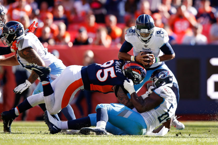 Tennessee Titans quarterback Marcus Mariota (8) is sacked by Denver Broncos defensive end Derek Wolfe (95) as guard Nate Davis (64) defends in the second quarter at Empower Field at Mile High.