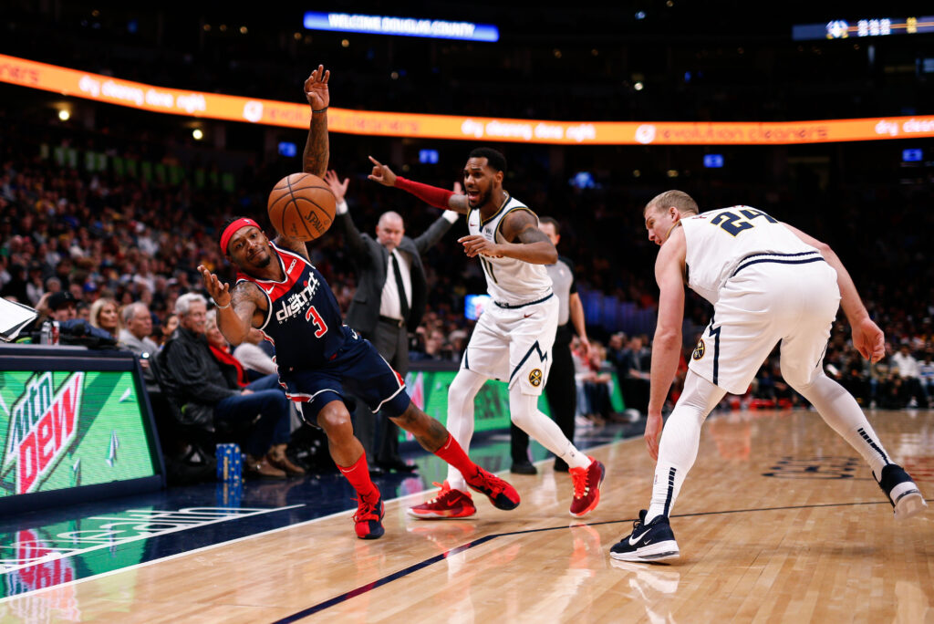 Washington Wizards guard Bradley Beal (3) reaches for a loose ball on a play with Denver Nuggets guard Monte Morris (11) and forward Mason Plumlee (24) in the third quarter at the Pepsi Center.