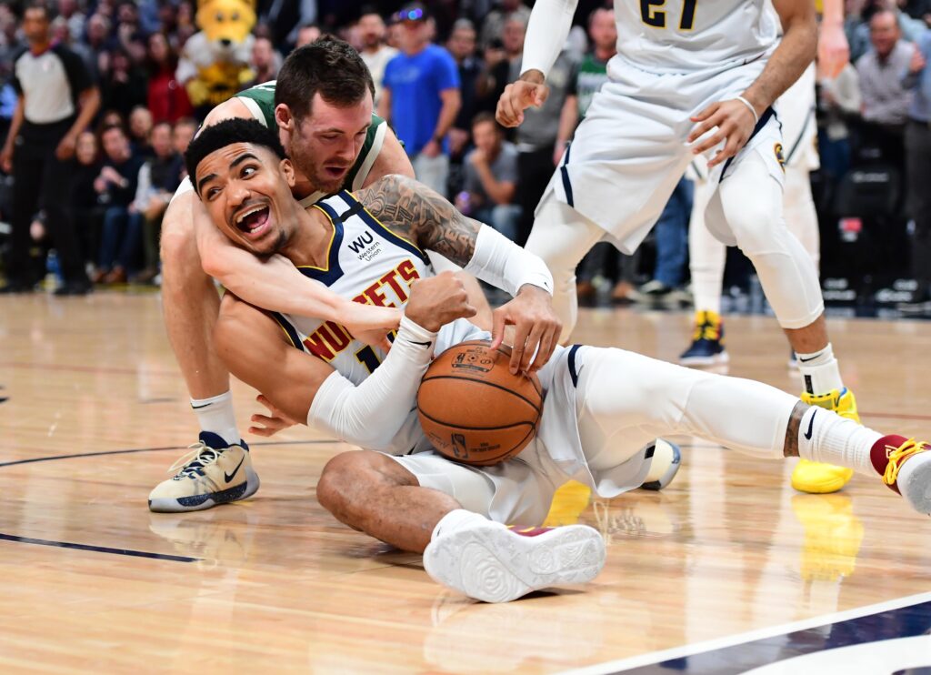 Milwaukee Bucks guard Pat Connaughton (24) reaches for the ball over the back of Denver Nuggets guard Gary Harris (14) in the first quarter at the Pepsi Center.