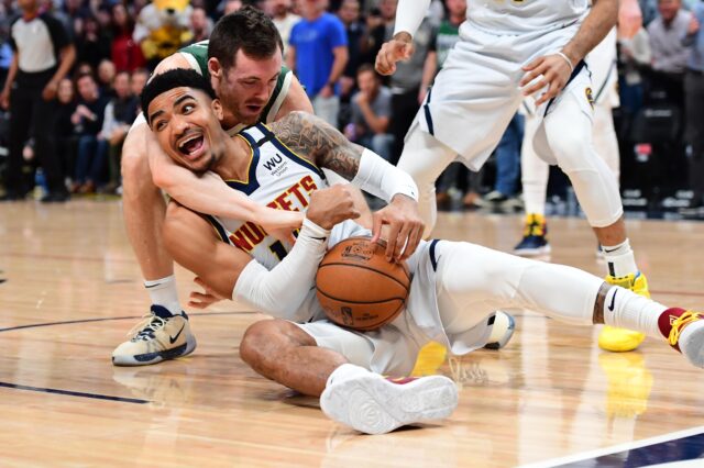 Milwaukee Bucks guard Pat Connaughton (24) reaches for the ball over the back of Denver Nuggets guard Gary Harris (14) in the first quarter at the Pepsi Center.