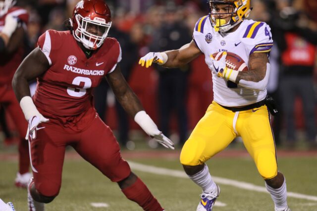 LSU Tigers running back Nick Brossette (4) rushes as Arkansas Razorbacks defensive lineman McTelvin Agim (3) defends in the first quarter at Donald W. Reynolds Razorback Stadium.