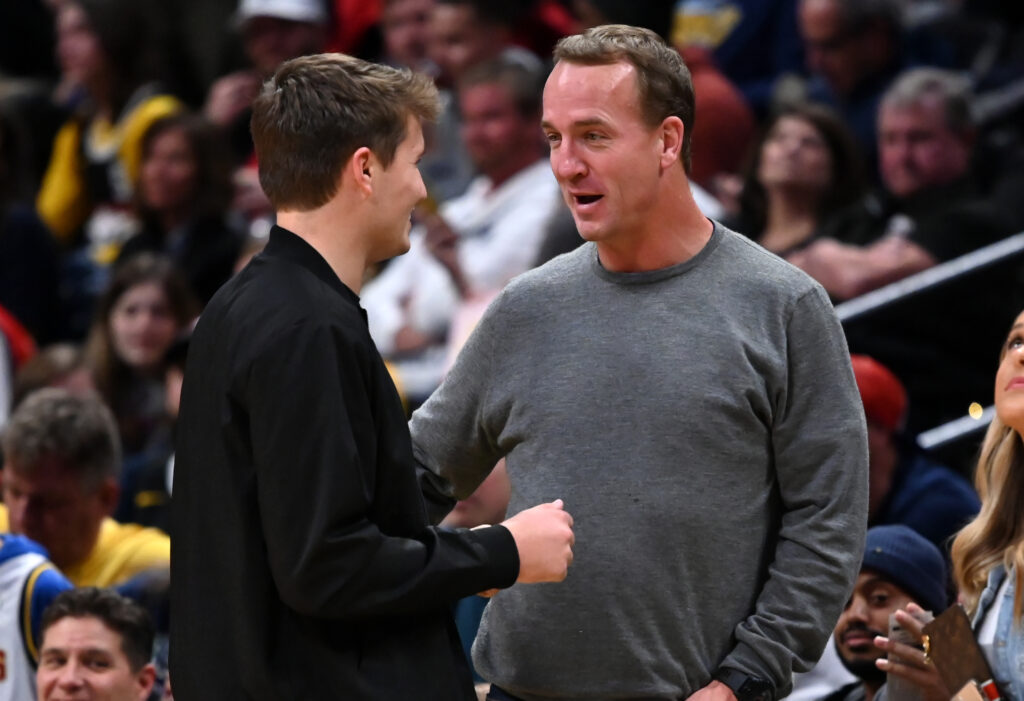 Denver Broncos quarterback Drew Lock (left) talks with retired NFL quarterback Peyton Manning (right) during the game between the Toronto Raptors against the Denver Nuggets at the Pepsi Center.