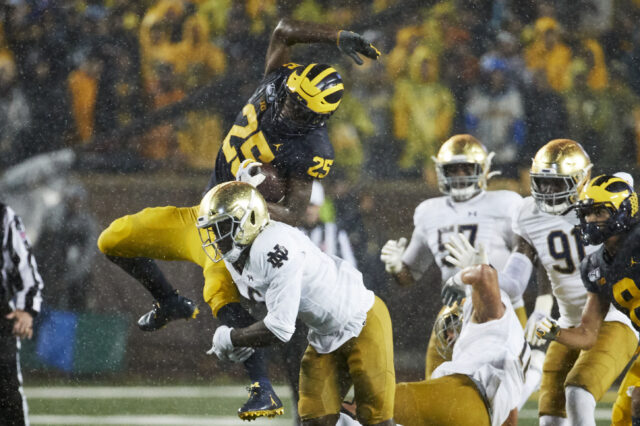 Michigan Wolverines running back Hassan Haskins (25) leaps over Notre Dame Fighting Irish linebacker Jeremiah Owusu-Koramoah (6) in the first half at Michigan Stadium.