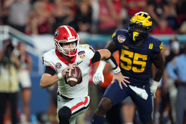 Georgia Bulldogs quarterback Stetson Bennett (13) scrambles against Michigan Wolverines linebacker David Ojabo (55) during the third quarter in the Orange Bowl college football CFP national semifinal game at Hard Rock Stadium.