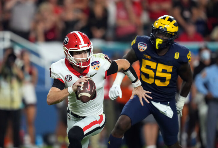 Georgia Bulldogs quarterback Stetson Bennett (13) scrambles against Michigan Wolverines linebacker David Ojabo (55) during the third quarter in the Orange Bowl college football CFP national semifinal game at Hard Rock Stadium.