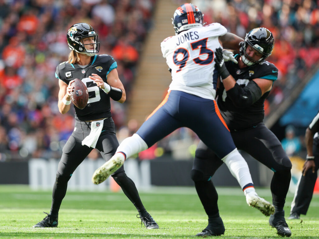 Jacksonville Jaguars quarterback Trevor Lawrence (16) looks to pass defedne3d by Denver Broncos defensive end Dre'Mont Jones (93) in the first quarter during an NFL International Series game at Wembley Stadium.