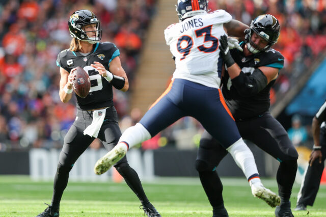 Jacksonville Jaguars quarterback Trevor Lawrence (16) looks to pass defedne3d by Denver Broncos defensive end Dre'Mont Jones (93) in the first quarter during an NFL International Series game at Wembley Stadium.