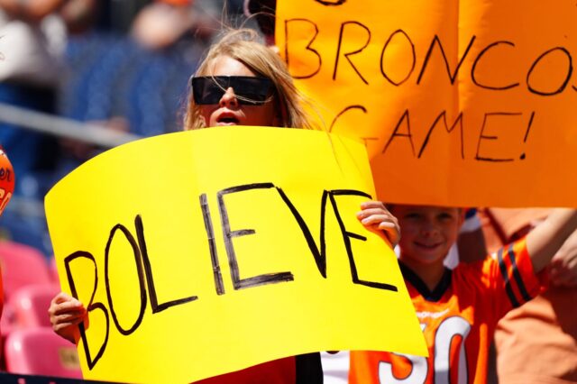 A fan holds a "BOLIEVE" sign at Broncos - Cardinals in 2024 preseason.