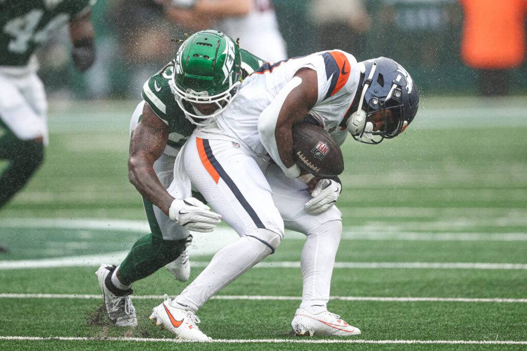 Denver Broncos running back Tyler Badie (28) fumbles after being hit by New York Jets linebacker Quincy Williams (56) during the first half at MetLife Stadium.