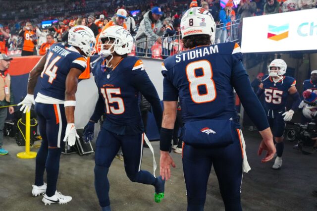 Nik Bonitto slaps hands with teammates Courtland Sutton and Jarrett Stidham as he runs onto the field at Mile High Stadium