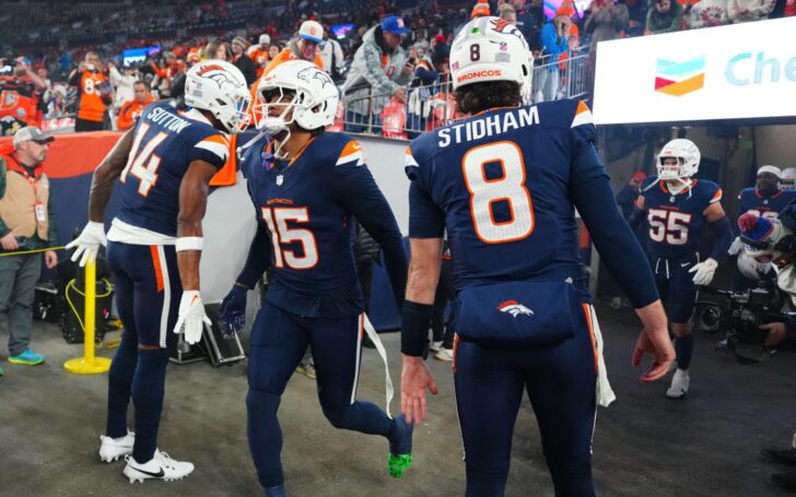 Nik Bonitto slaps hands with teammates Courtland Sutton and Jarrett Stidham as he runs onto the field at Mile High Stadium