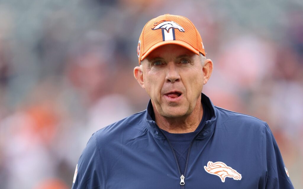 Sean Payton in an orange Broncos hat and blue zip up.