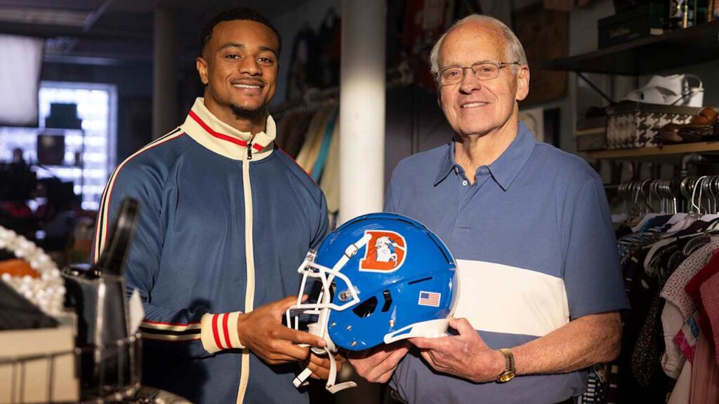 Pat Surtain II and Randy Gradishar pose with the Denver Broncos throwback helmet.