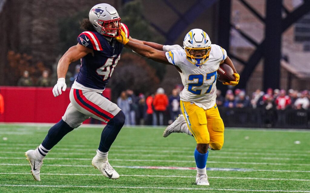 JK Dobbins stiff arms a Patriots player.