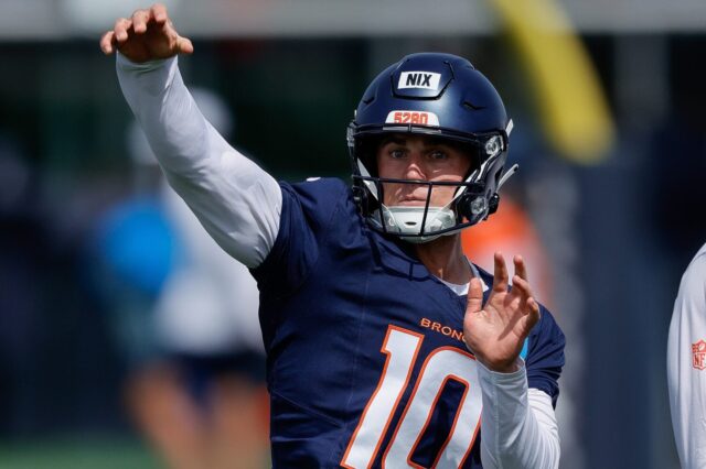 Bo Nix passes at training camp. He wears a Broncos blue jersey and a long sleeve shirt underneath, with a Broncos helmet minus the logo.