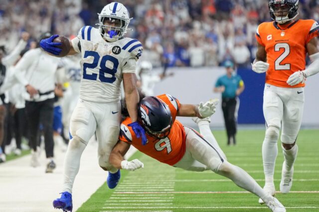 Jonathan Taylor runs and is knocked out of bounds by Talanoa Hufanga of the Broncos.